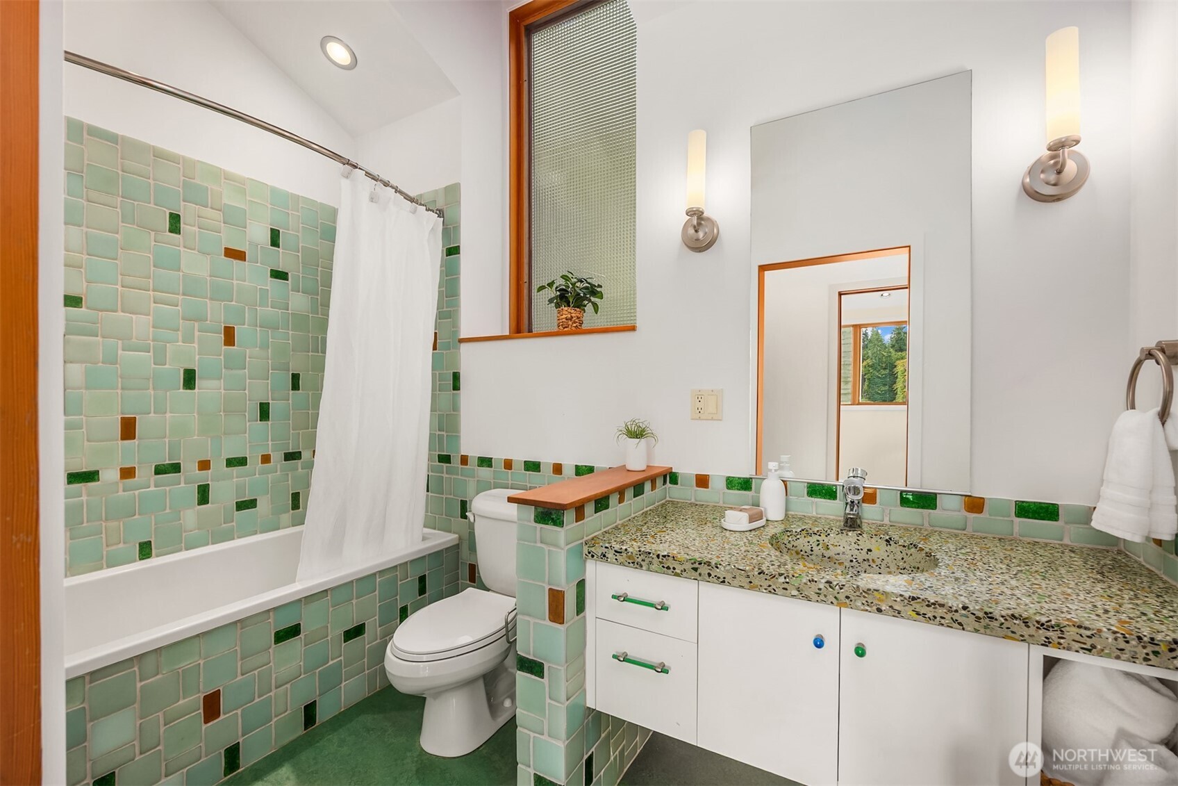 One of two matching full bathrooms in the bedroom wing featuring unique concrete and beach glass countertops, recycled glass shower tiles, deep Zuma soaking tub, and Grohe fixtures.