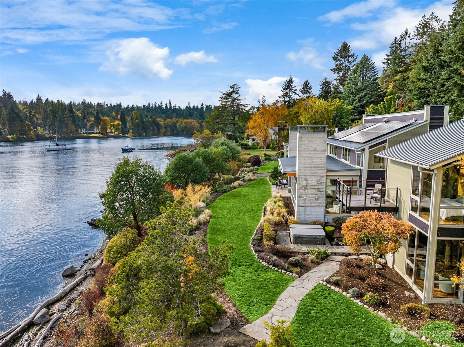 Thoughtfully curated grounds with fruit trees, ornamental plantings, raised garden beds, and a lush lawn with paths to the beach.
