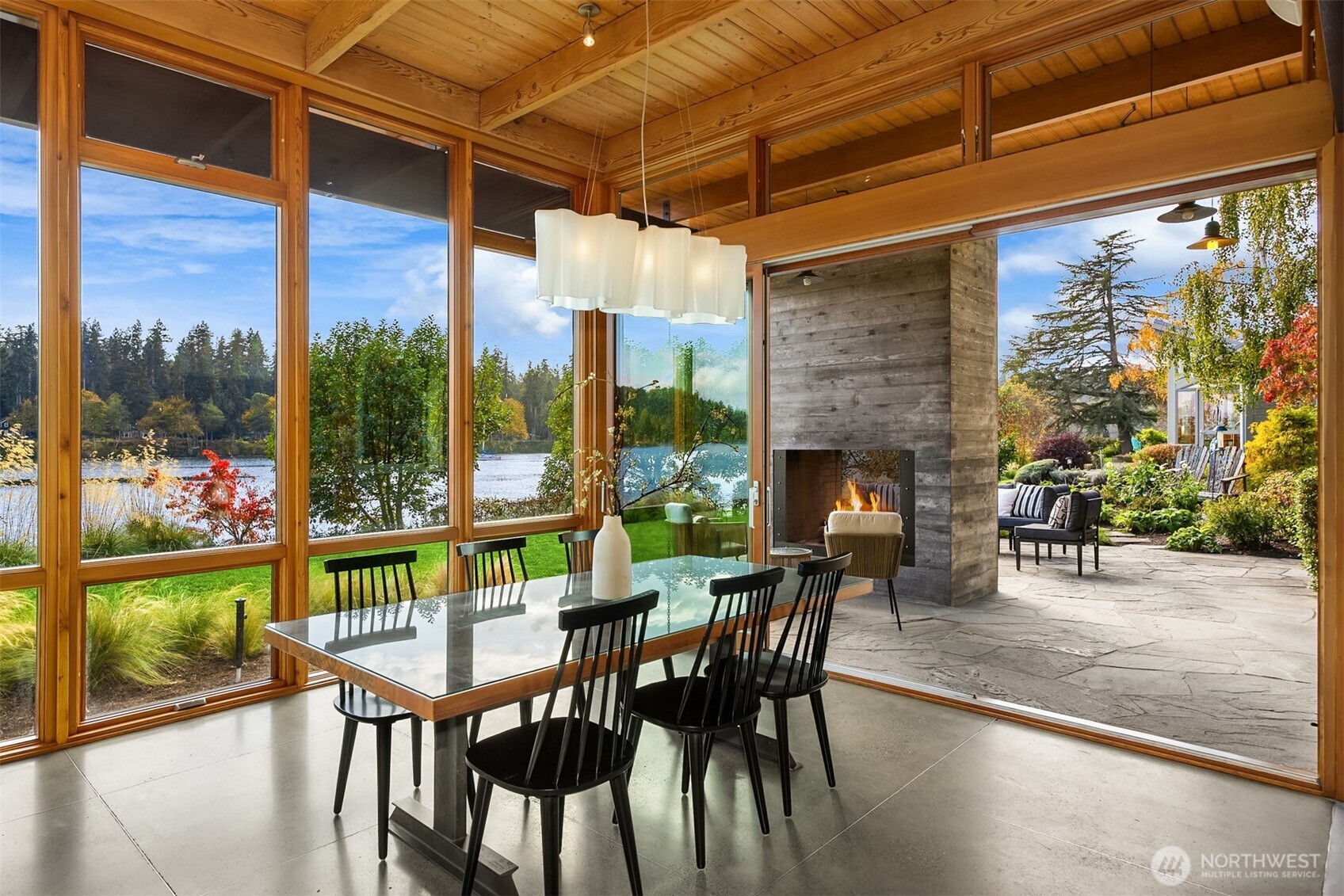 The west wall of the dining/great room opens seamlessly to a stone patio featuring a second steel-and-concrete fireplace, perfect for outdoor entertaining!
