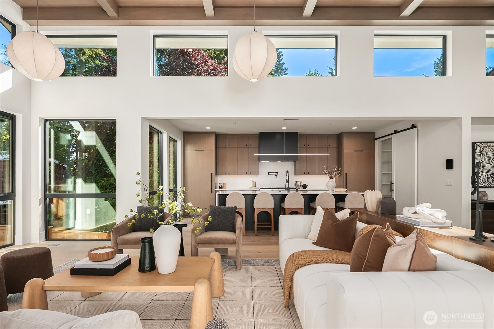 A double-waterfall quartz island anchors the kitchen, ideal for gathering and entertaining.  Custom oak cabinetry and a commanding matte black range hood add elegance and drama.