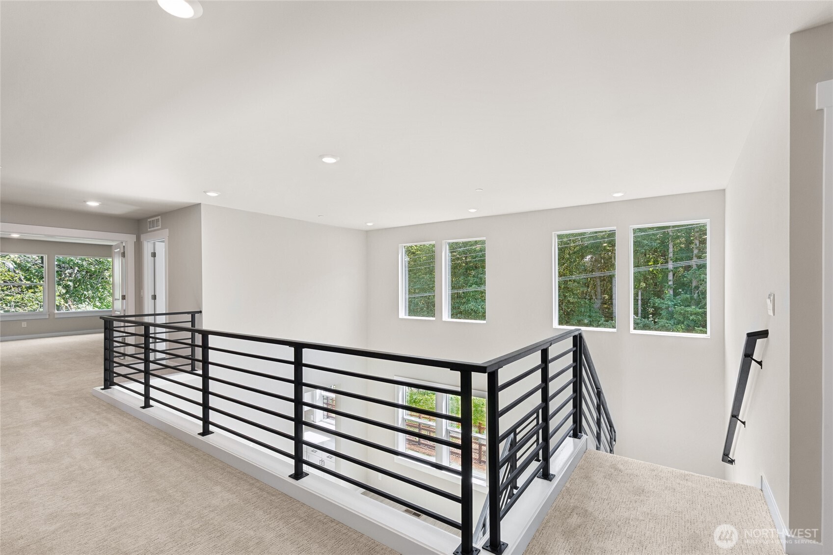 Open and airy upstairs hallway looking down to formal dining room.