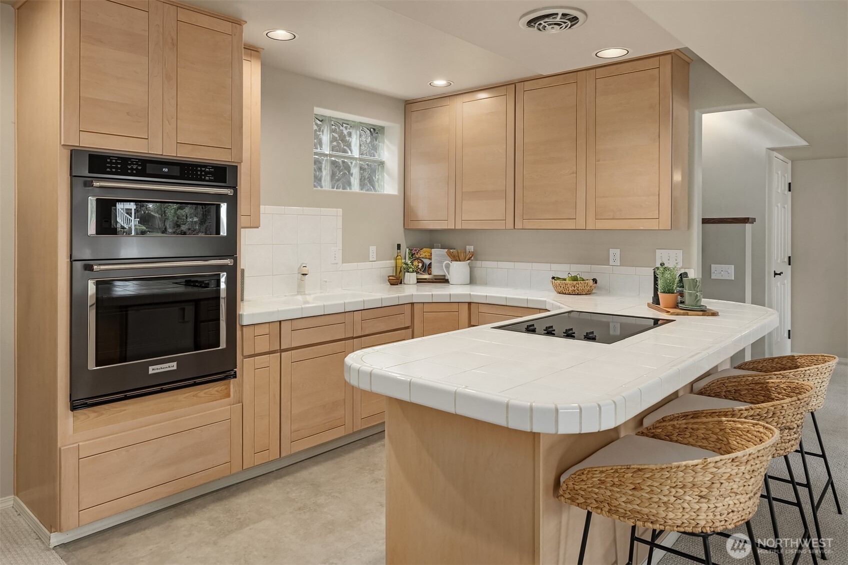 A fully equipped secondary kitchen with maple cabinetry, a Maytag cooktop, KitchenAid oven and microwave, and under-counter refrigeration—designed for effortless hosting or independent living.