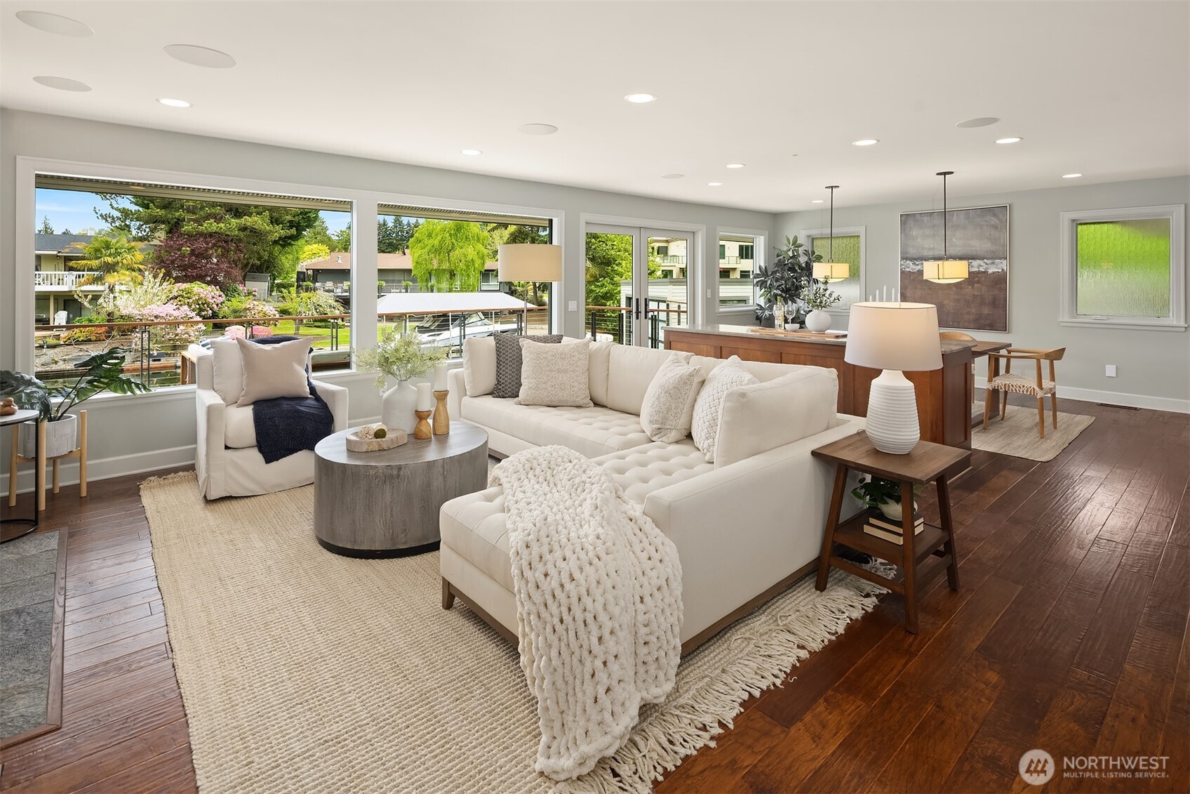 Morning light fills the space, coffee in hand, doors open to the deck—an easy, natural flow from kitchen to living to water that defines daily life here.