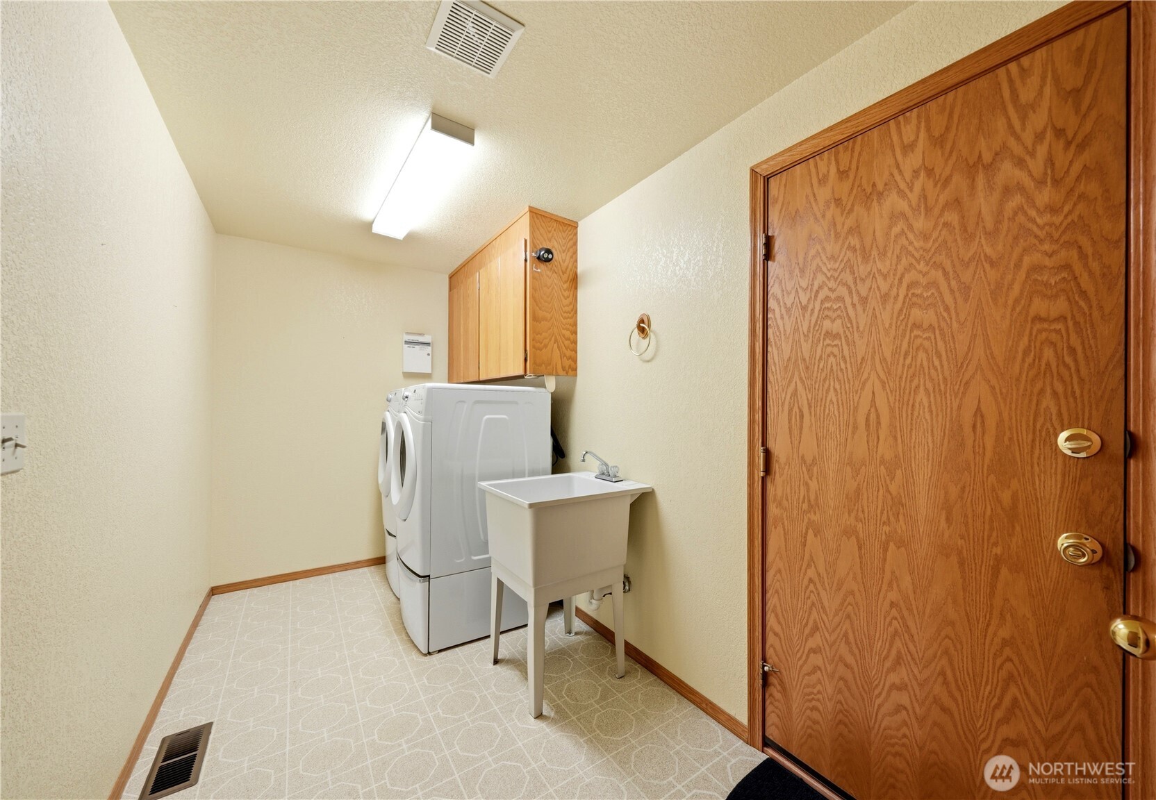 Here's the laundry room with full size appliances on storage pedestals, along with a utility sink and storage cupboards. The door to the right heads out to the garage.