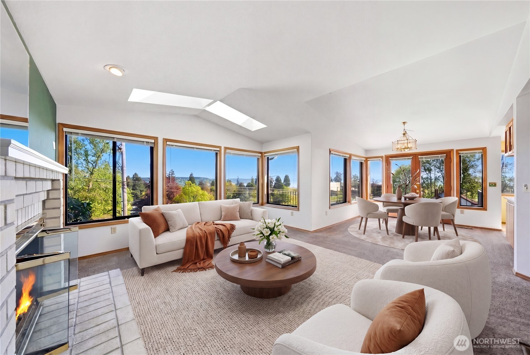 Amazing living room/dining room with skylights, fireplace and oh yeah.. a few windows to enjoy that expansive view! (This photo is virtually staged).
