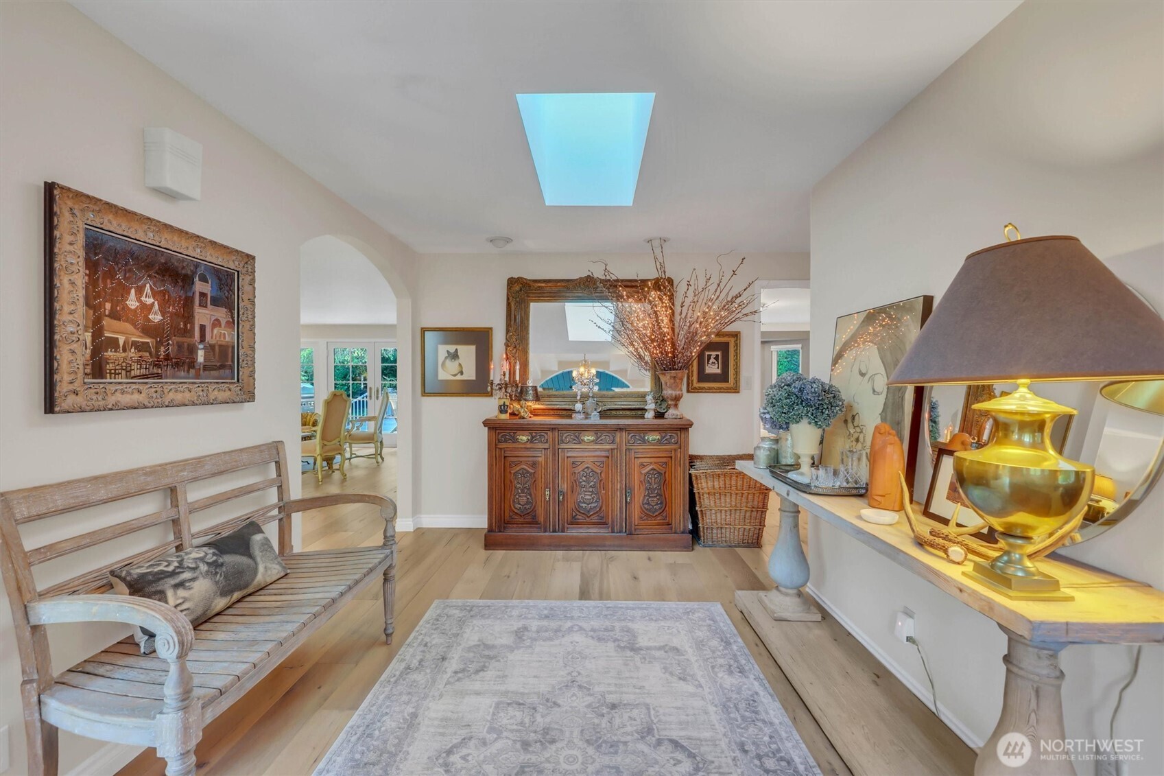 Enter the double doors to the foyer with gleaming, wide plank hardwood floors and skylight.