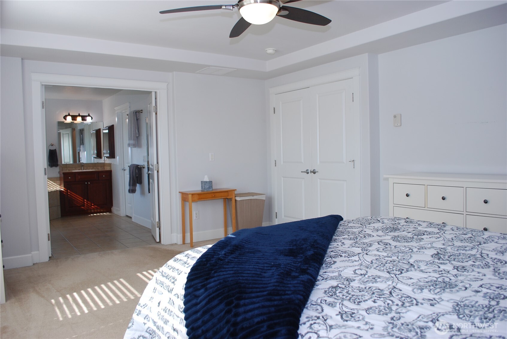 Looking across the primary suite, through the French doors leading into the five piece bathroom suite.