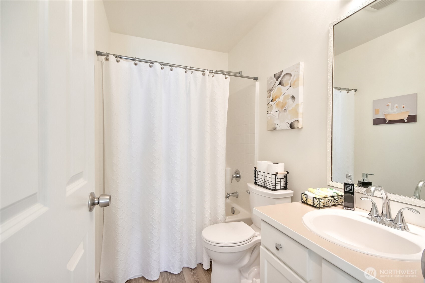 Hall bathroom with newer flooring, toilet, sink, fixtures & mirror.
