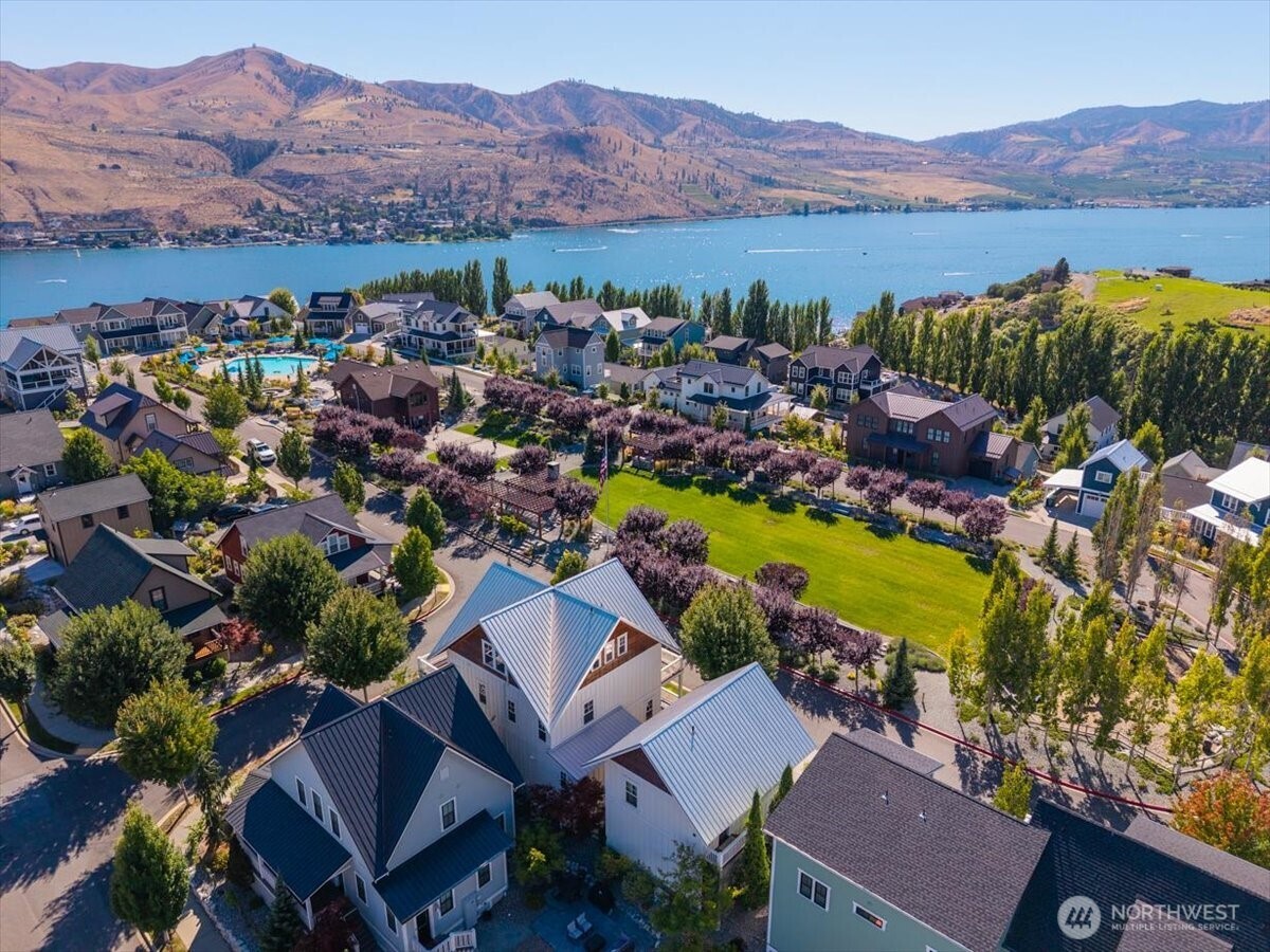 Aerial view of home looking SW overlooking the Lookout's Hilltop Park with grassy lawn area, playground, outdoor fireplace, BBQ area, pickleball court, clubhouse, pool and hot tub.