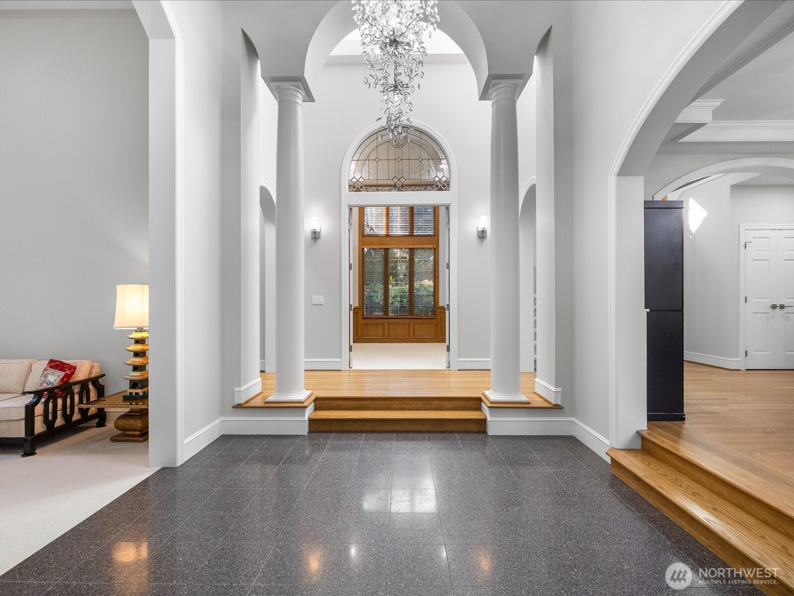 Dramatic foyer with vaulted ceiling, extravagant chandelier, and freshly painted walls and ceiling.