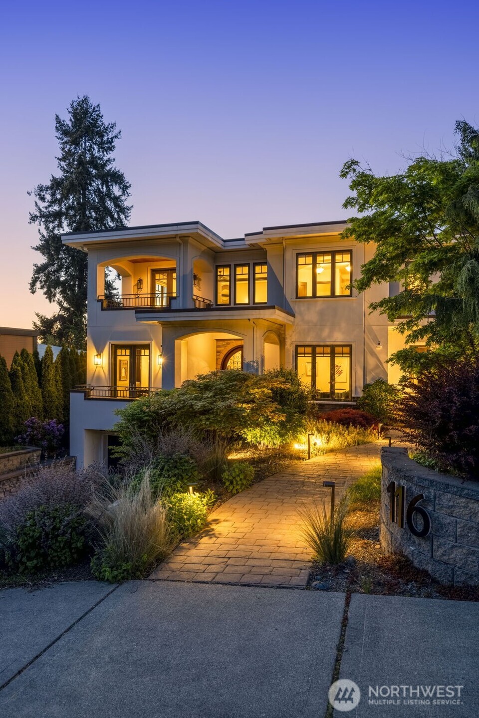 Front photo: Warm evening view of the home's grand entry and architectural detailing, illuminated against the Pacific Northwest sky.