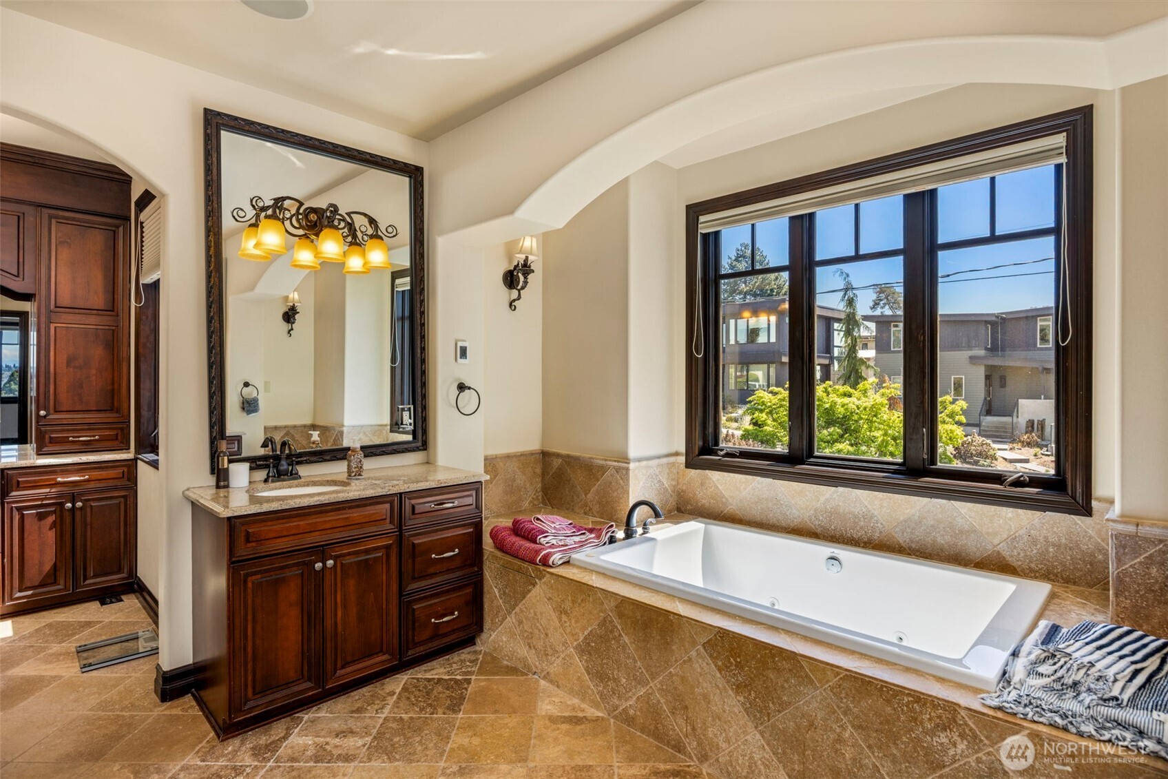 Primary bathroom: Spa-inspired Primary bath with deep soaking tub set beneath a picture window, framed by rich wood cabinetry. Heated floors.