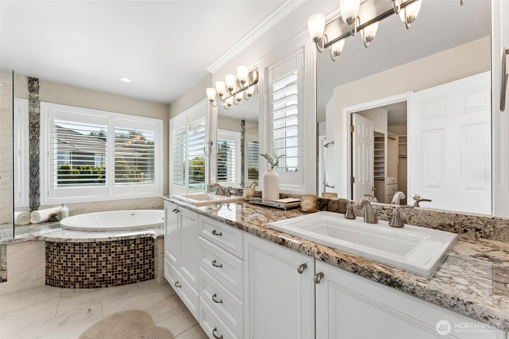 Remodeled primary bathroom with dual sinks, jetted tub, and walk-in shower
