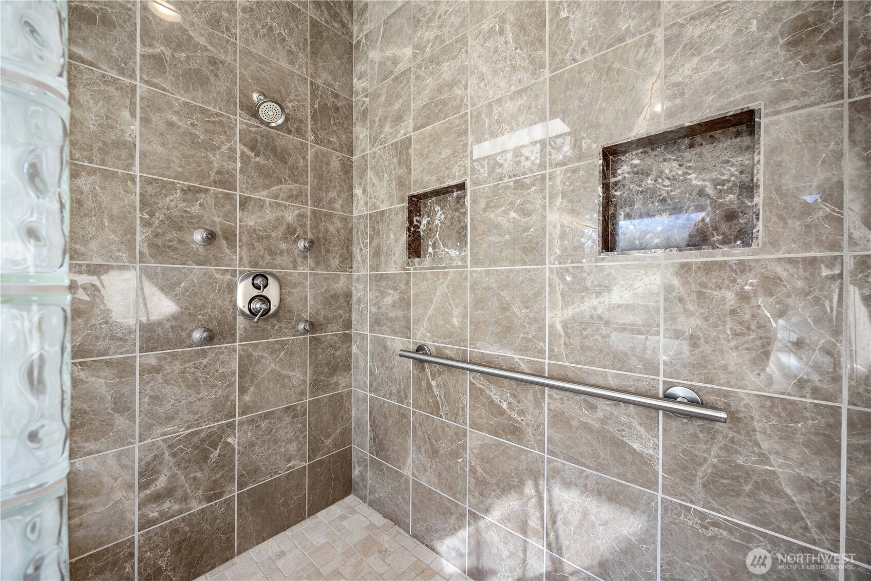 Spa-inspired primary ensuite featuring a massive walk-in shower with dual shower heads, elegant tile surrounds, and built-in niches. Designed for a luxurious experience, this expansive shower retreat blends modern finishes with functionality for everyday comfort.