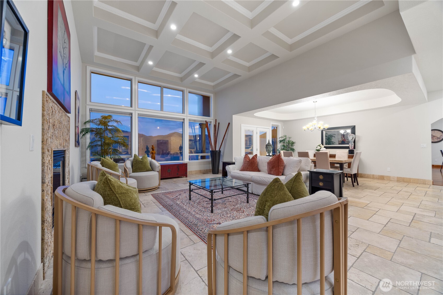 Expansive great room with dramatic coffered ceilings and a wall of windows capturing sweeping Lake Chelan and mountain views. Elevated design details, including custom millwork, elegant railings, and warm natural light, create a refined yet inviting space. The open-concept layout seamlessly connects living and dining areas ideal for entertaining while taking in the breathtaking scenery.