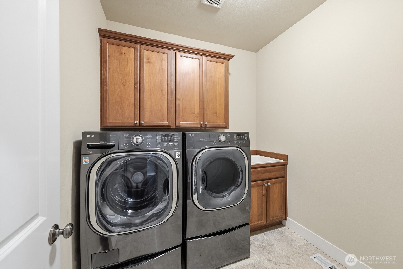 Laundry room has utility sink and cabinets