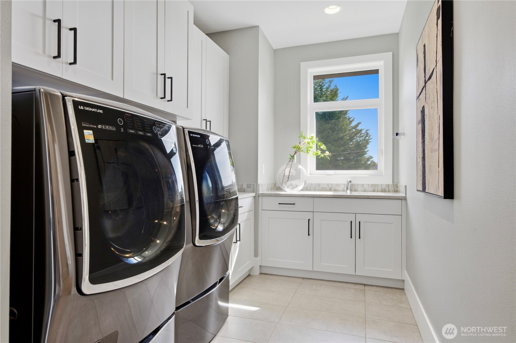 Upstairs laundry room with abundant storage, natural light, and generous counter space for added convenience