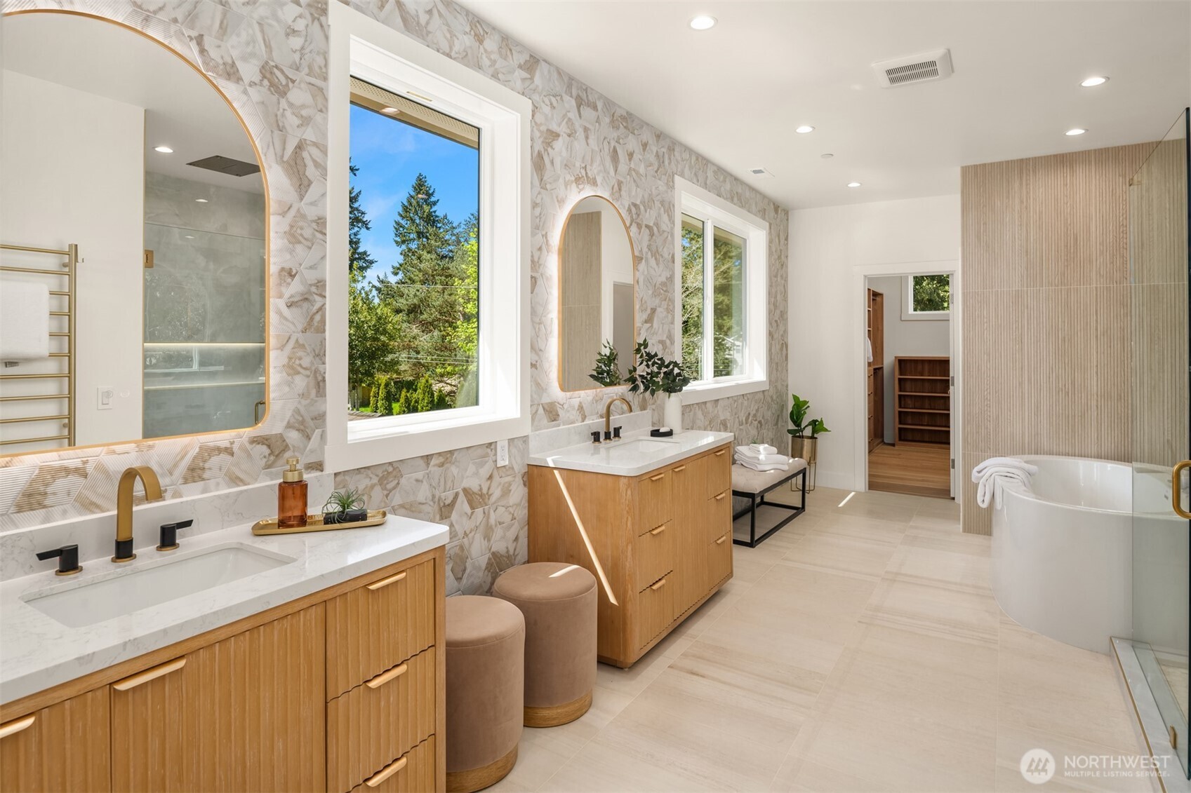 Beautiful primary bath loaded with upgrades - high-end Rodin hydro system tub, designer tiles, vanity with built-in hair-styling station, rain shower, shower niche background lighting, and more!