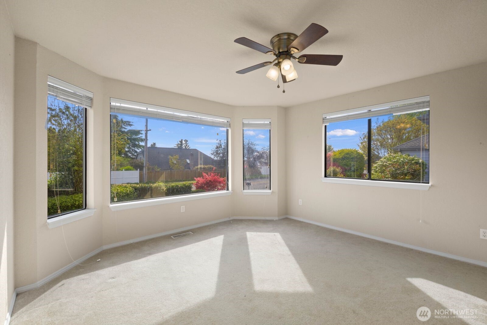 Living space with a corner of large windows bringing in natural light and views of the surrounding yard