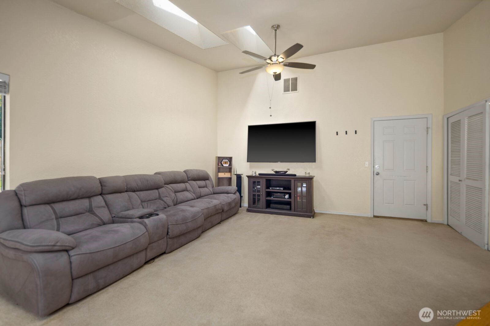 Additional living area with vaulted ceilings, ceiling fan, and overhead skylights adding natural brightness