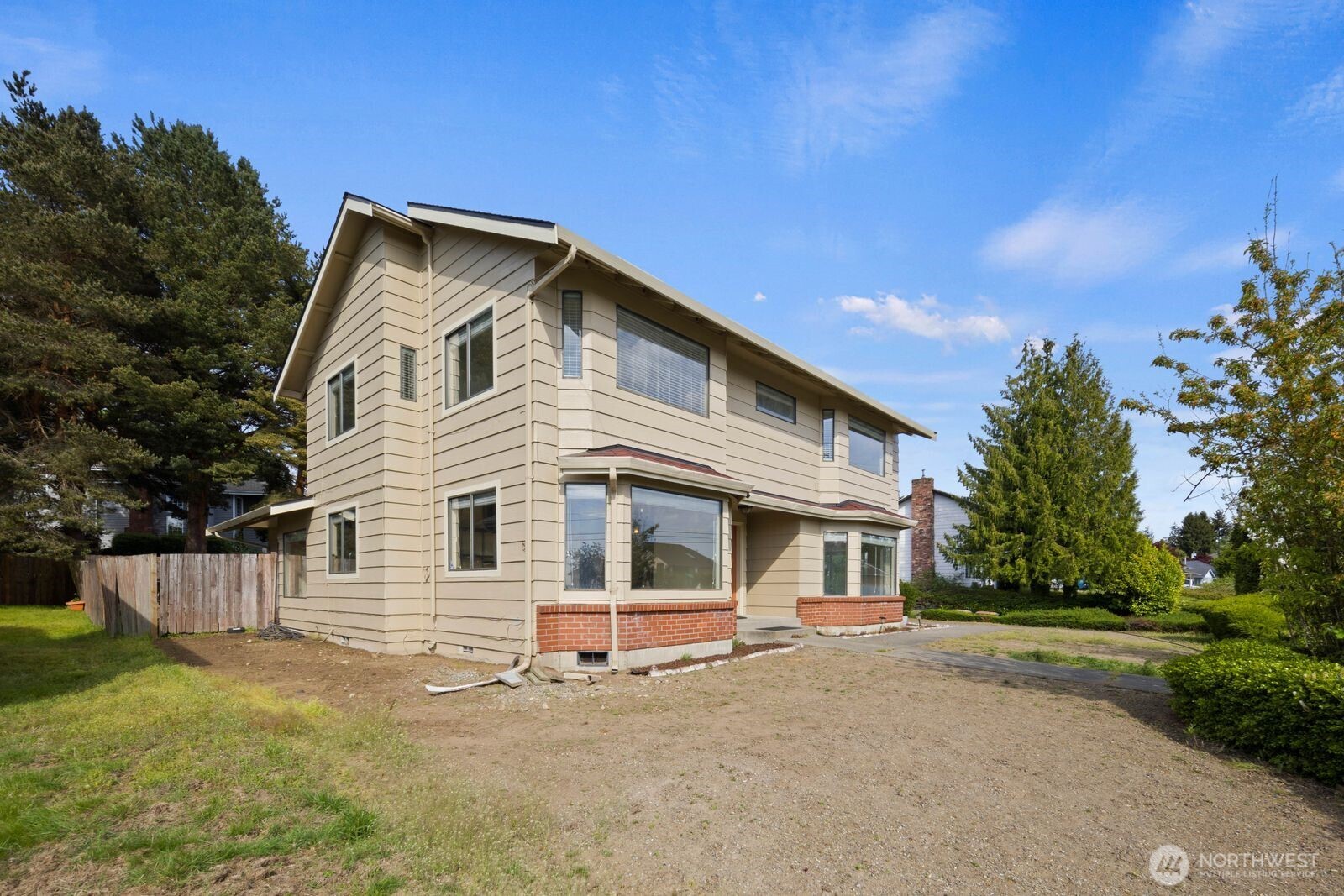 Side view of the home showing the two-story layout, extended rooflines, and surrounding yard space