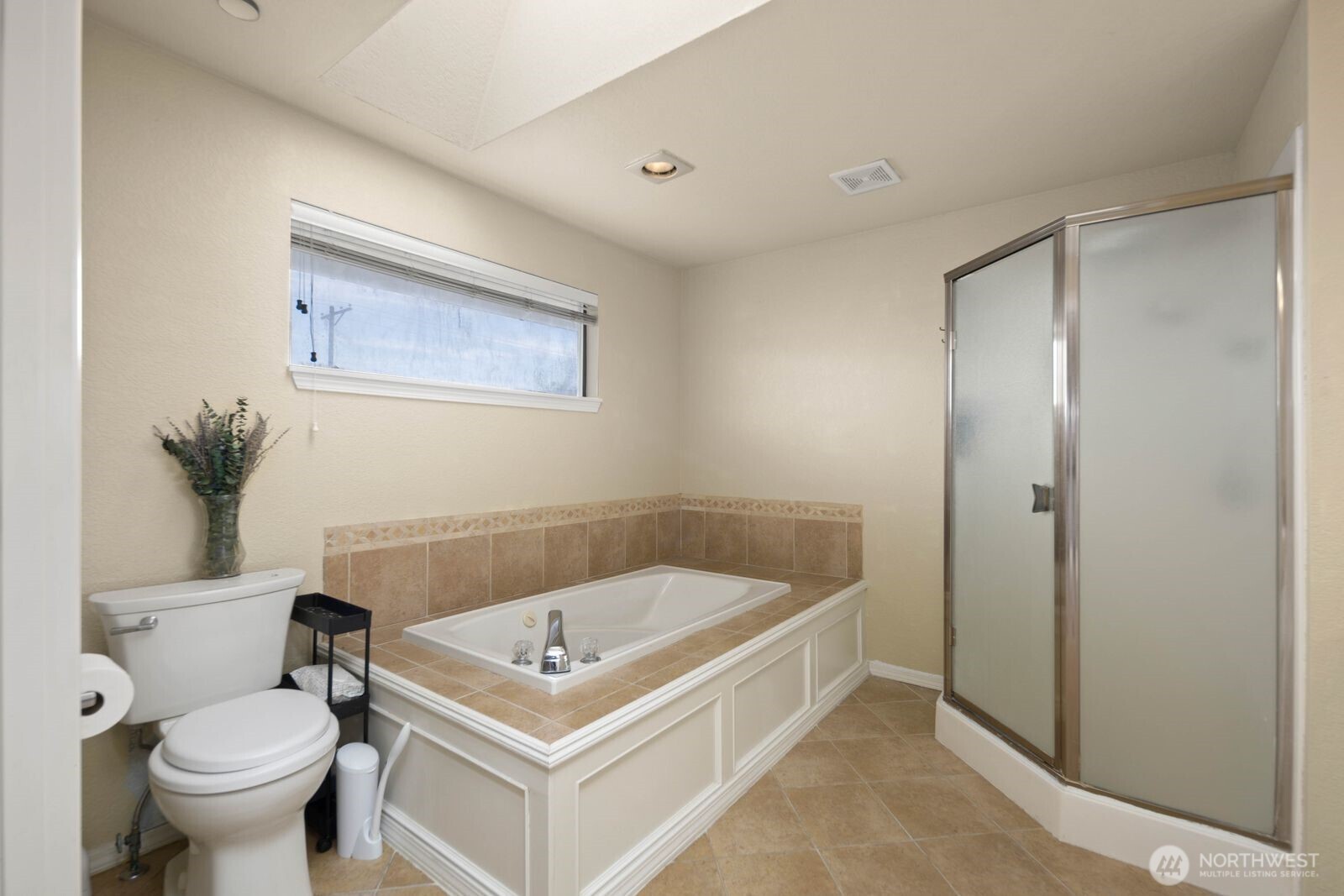 Primary bathroom with soaking tub, separate shower, and tile finishes.