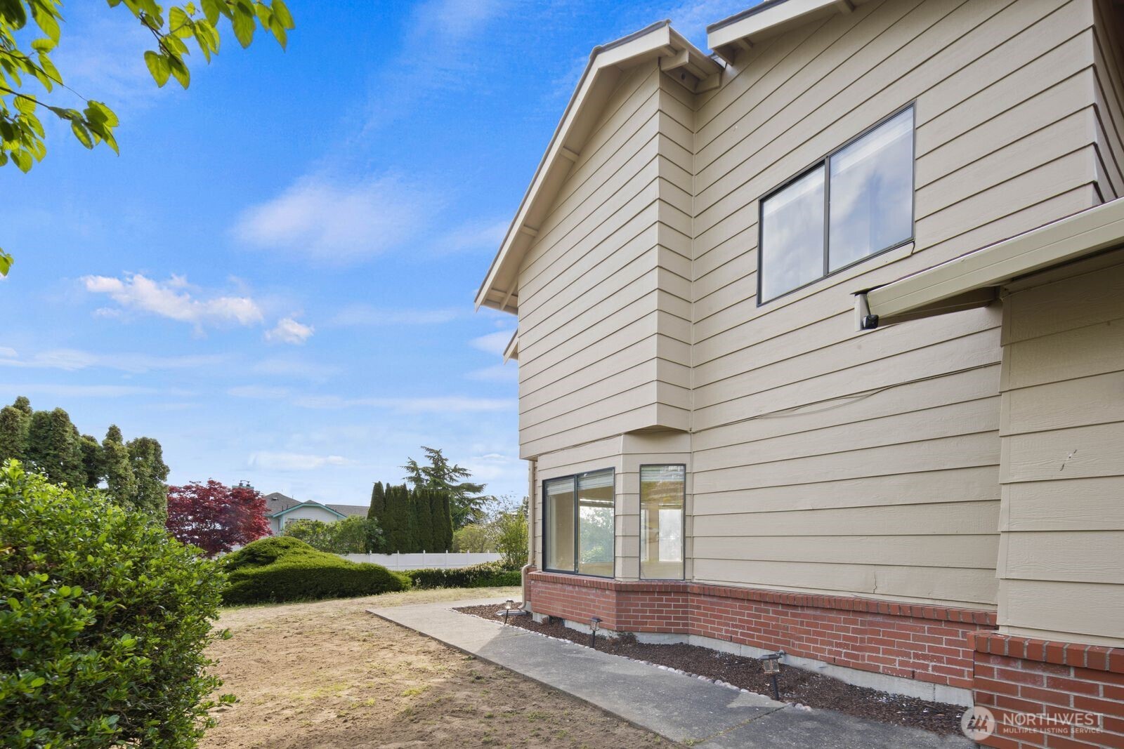 Side and rear exterior with walkway access, landscaped border, and additional yard space.