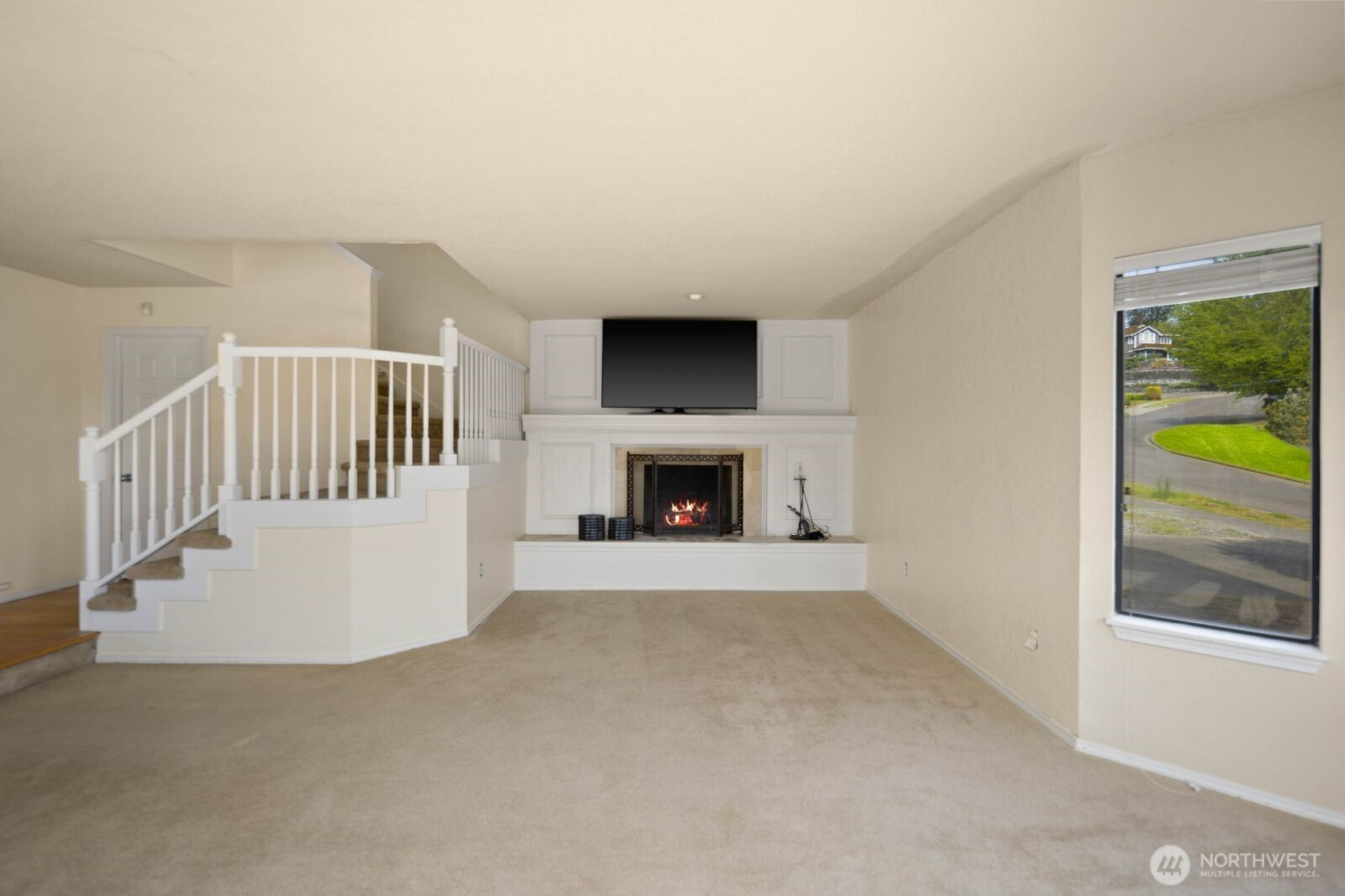 Living area centered around a fireplace with built-in surround and stair access leading to the upper level