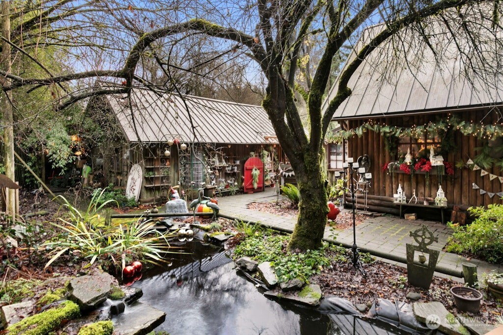 Original home on the property is to the left and 1936 built log home is to the right. View from front gated entry as you enter over the bridge over the Koi pond.