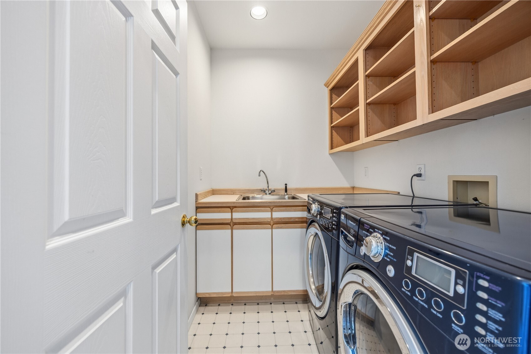Laundry room with side-by-side washer and dryer, and upper shelving for storage. Clean, functional layout with built-in organization.