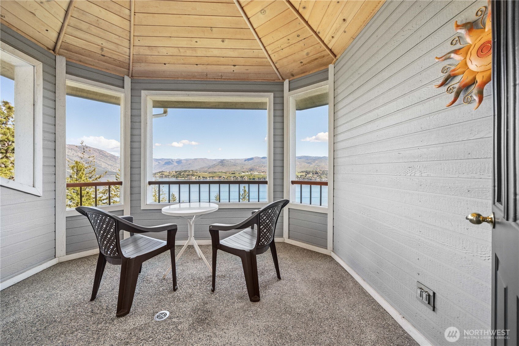 Crows nest upper balcony featuring a covered seating area with table and chairs, surrounded by railing to take in elevated lake and mountain views.