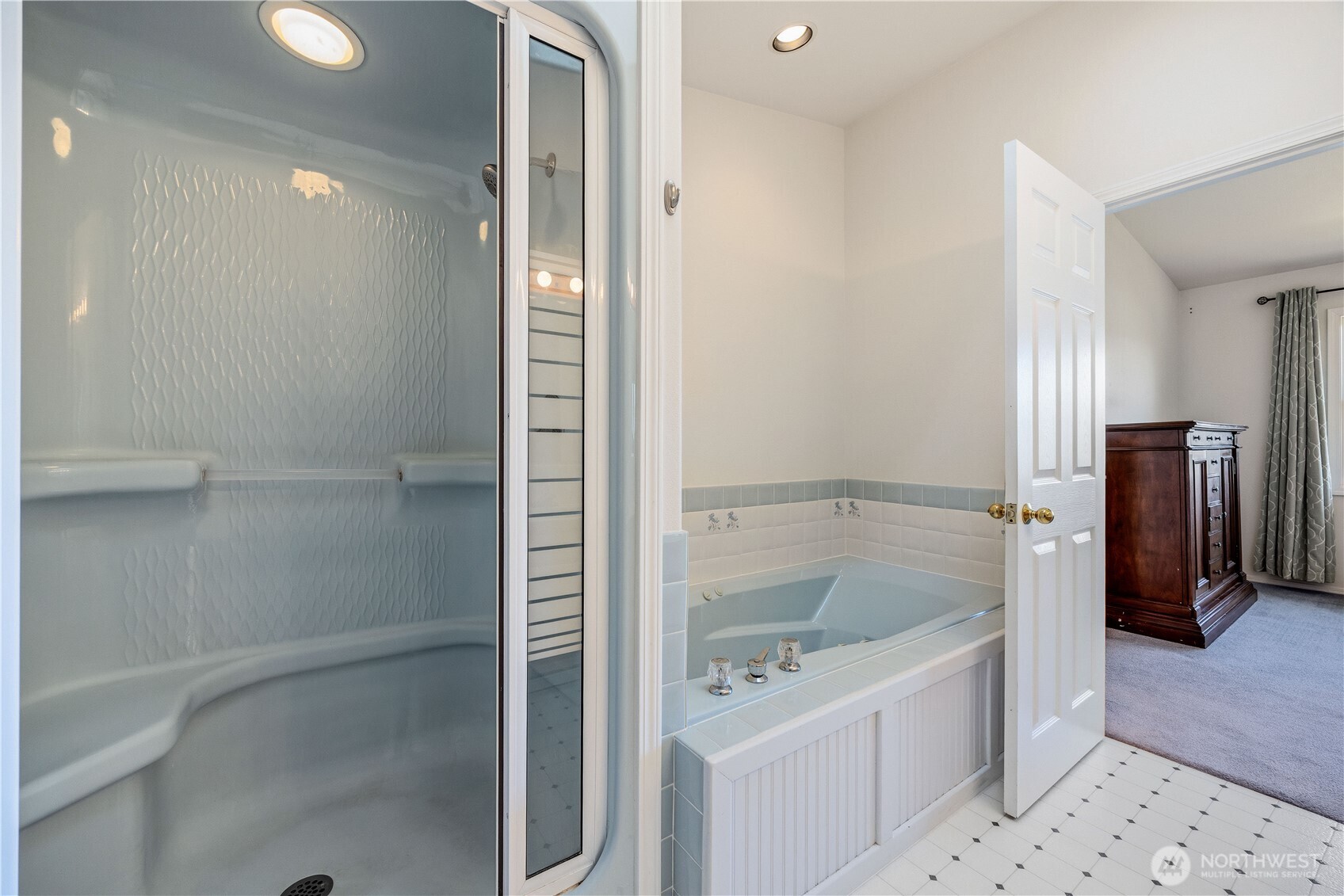 Primary bath featuring a glass-enclosed shower and jetted soaking tub, with bright finishes and a clean, functional layout.