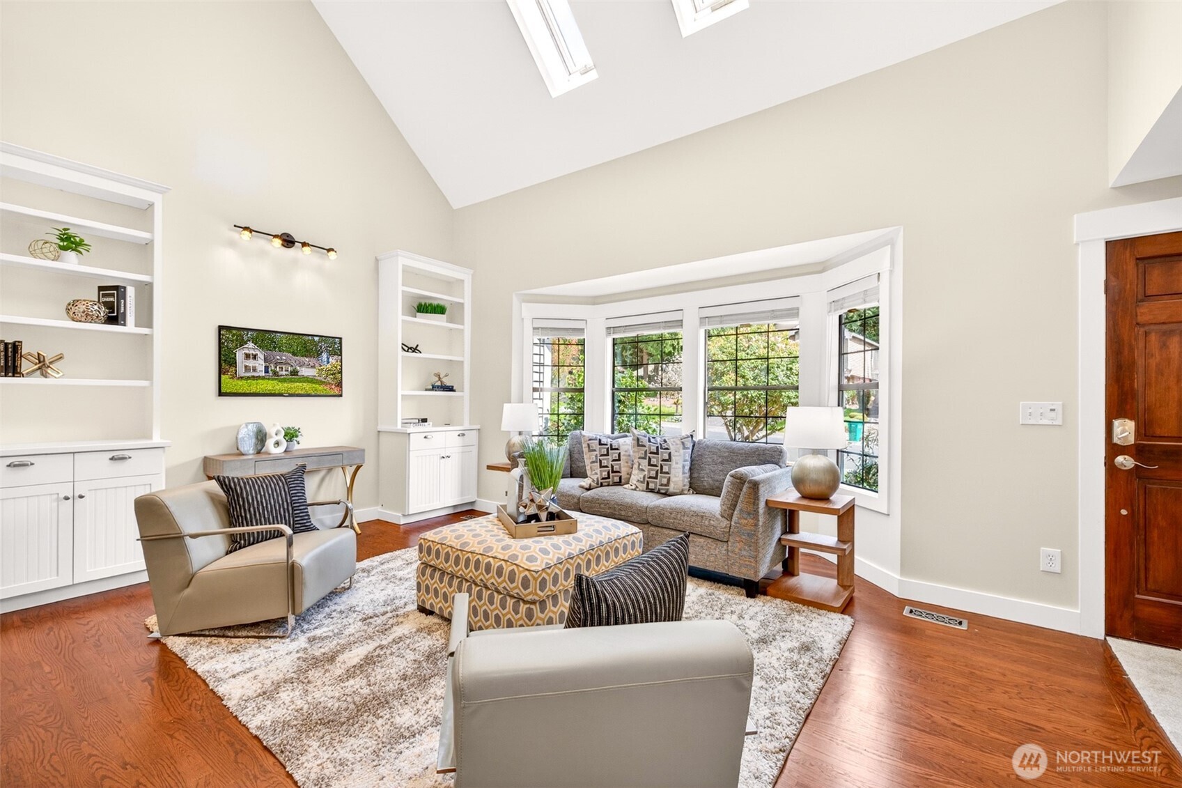 Skylights, a wraparound bay window, and custom built-ins frame a sun-filled living room designed for relaxed evenings and quiet weekend mornings alike.