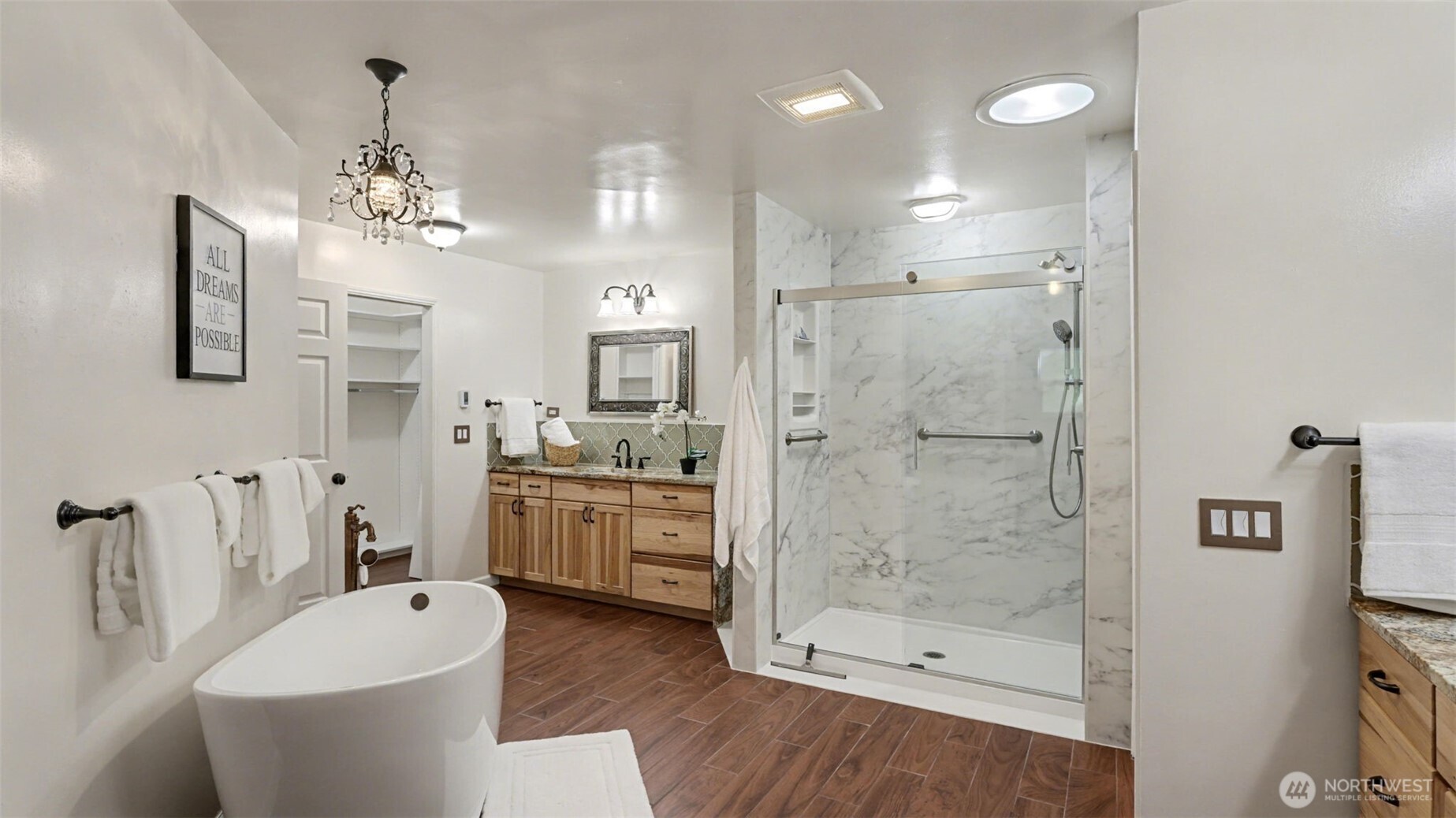 Spa-like bath with heated floors, separate sinks, and granite countertops.