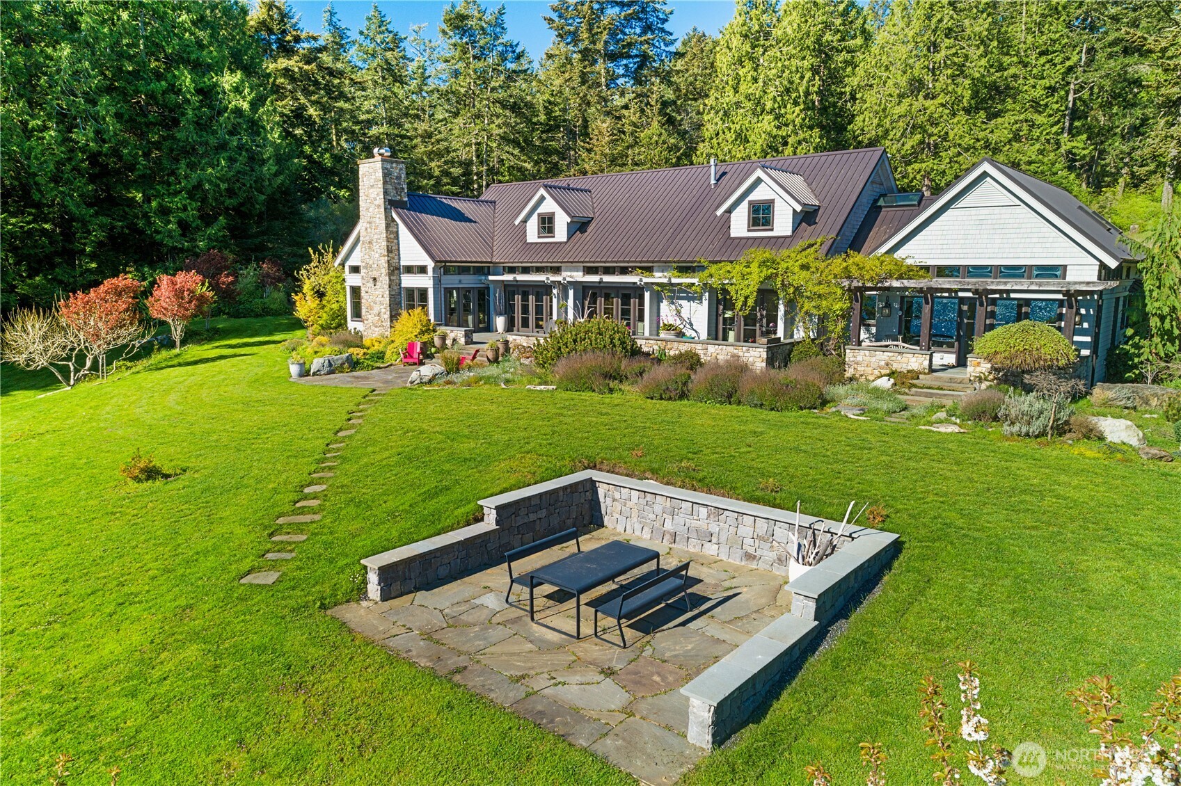 A thoughtfully placed mid-yard patio enhances the outdoor experience, ideal for grilling and hosting, with distinct spaces that invite guests to mingle and relax throughout the grounds.