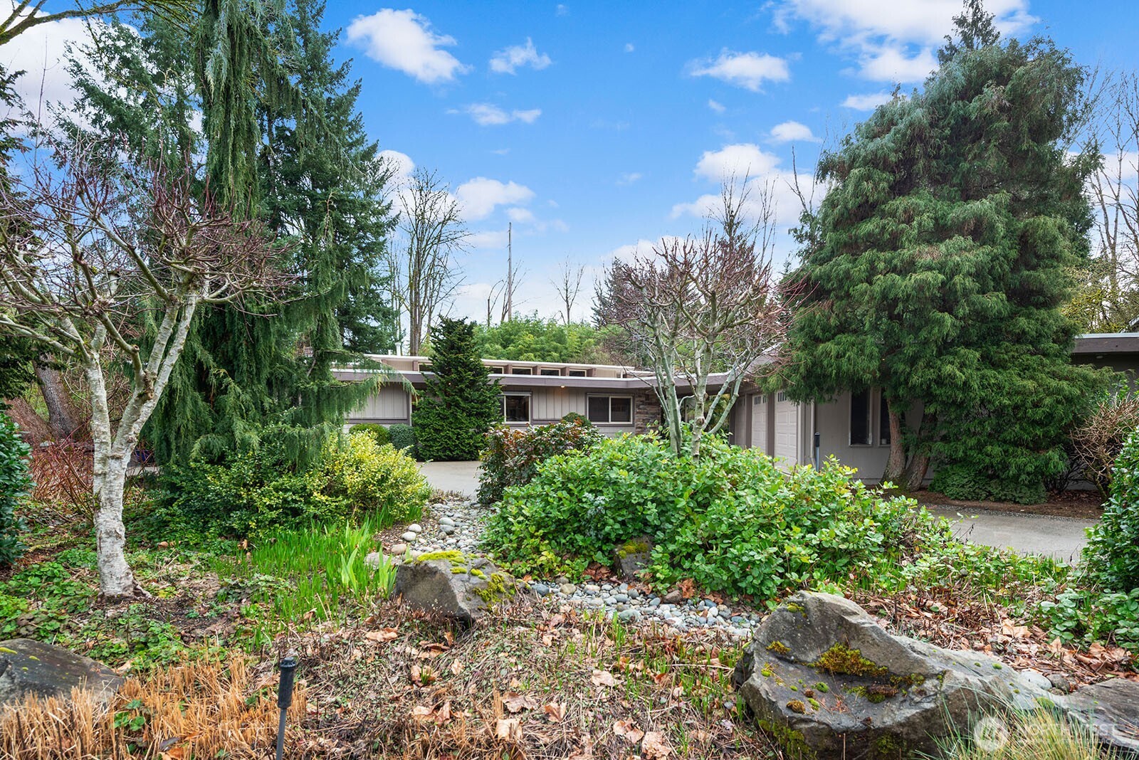 Intentional native landscaping of rocks, brush, trees, grasses, and flowers are featured throughout the property.