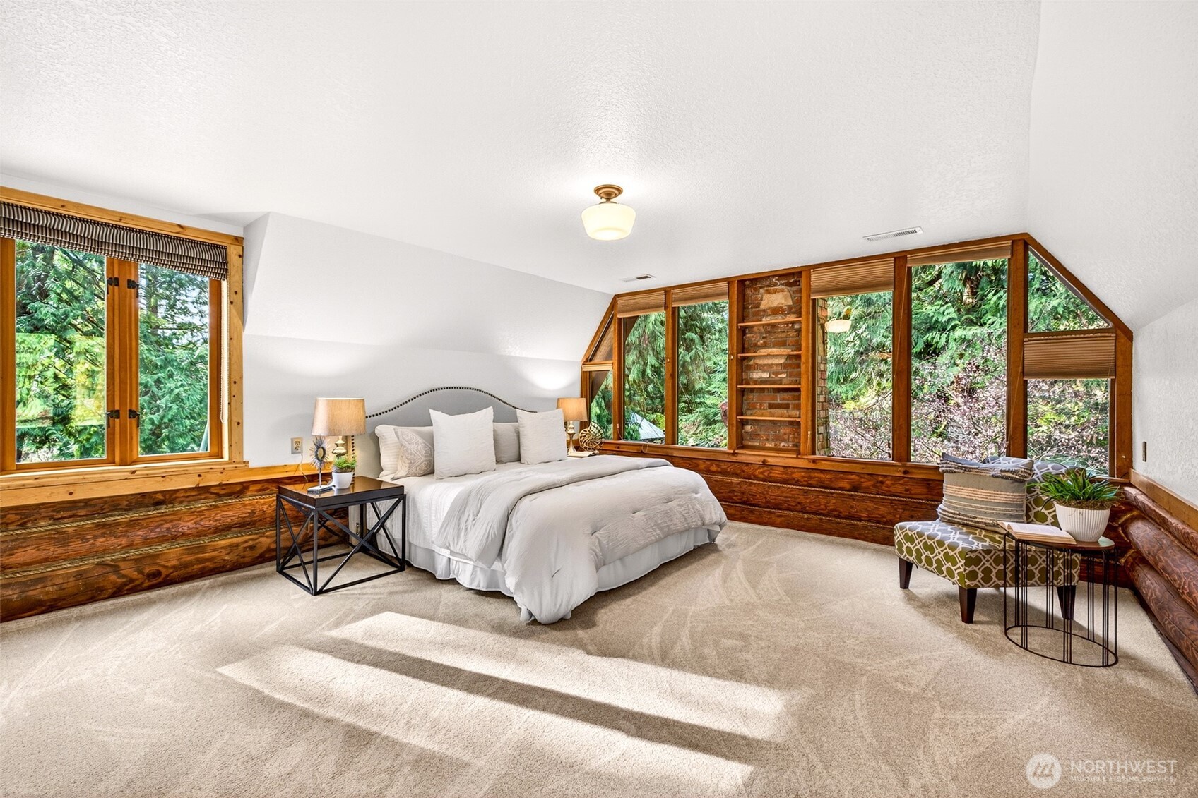 The primary bedroom is a true sanctuary — a full wall of gable windows floods the space with natural light and treetop views, while the generous layout and warm wood trim deliver the peaceful, private retreat every owner deserves.