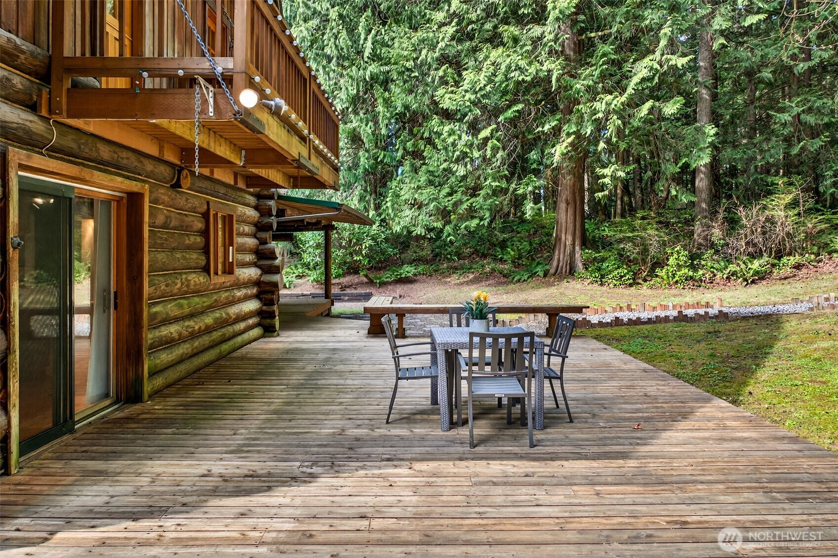 The lower-level deck opens directly from the main living area and backs to towering Pacific Northwest evergreens — a generous outdoor entertaining space where the boundary between the home and its 3.71 private acres simply disappears.
