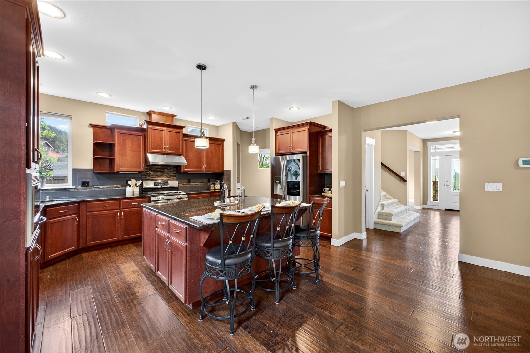 Chef’s kitchen features stainless steel appliances, granite countertops, tile backsplash, a large pantry, and an abundance of cabinet and counter space. The oversized island provides impressive prep space and casual dining.
