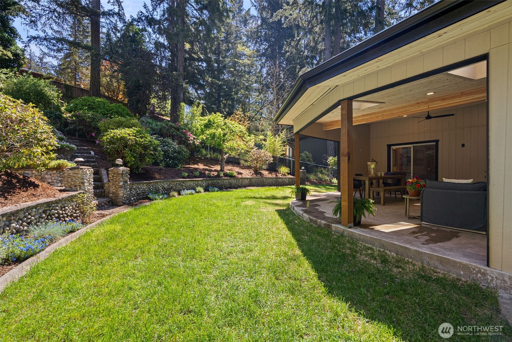 Tiered yard with mature landscaping and idyllic greenery provides a peaceful and private setting.
