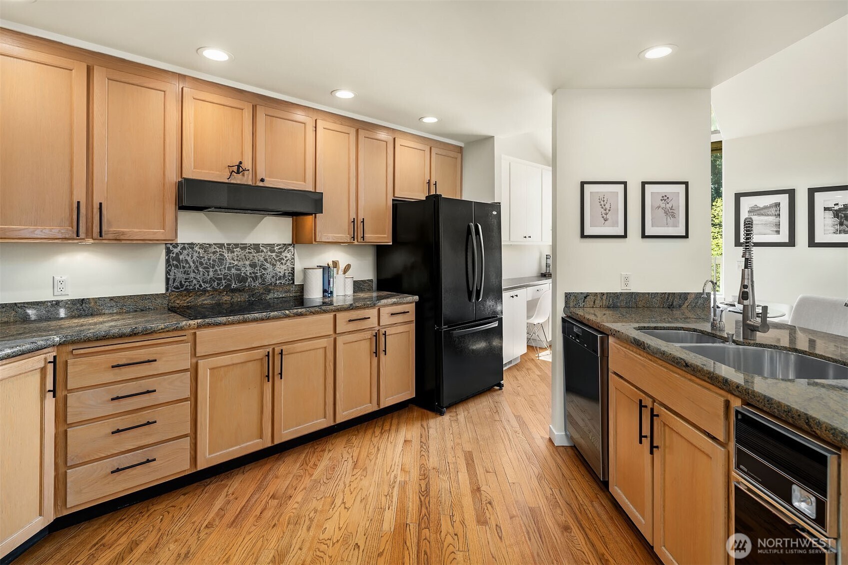 Updated kitchen offers abundant cabinetry with granite stone counters and designer backsplash