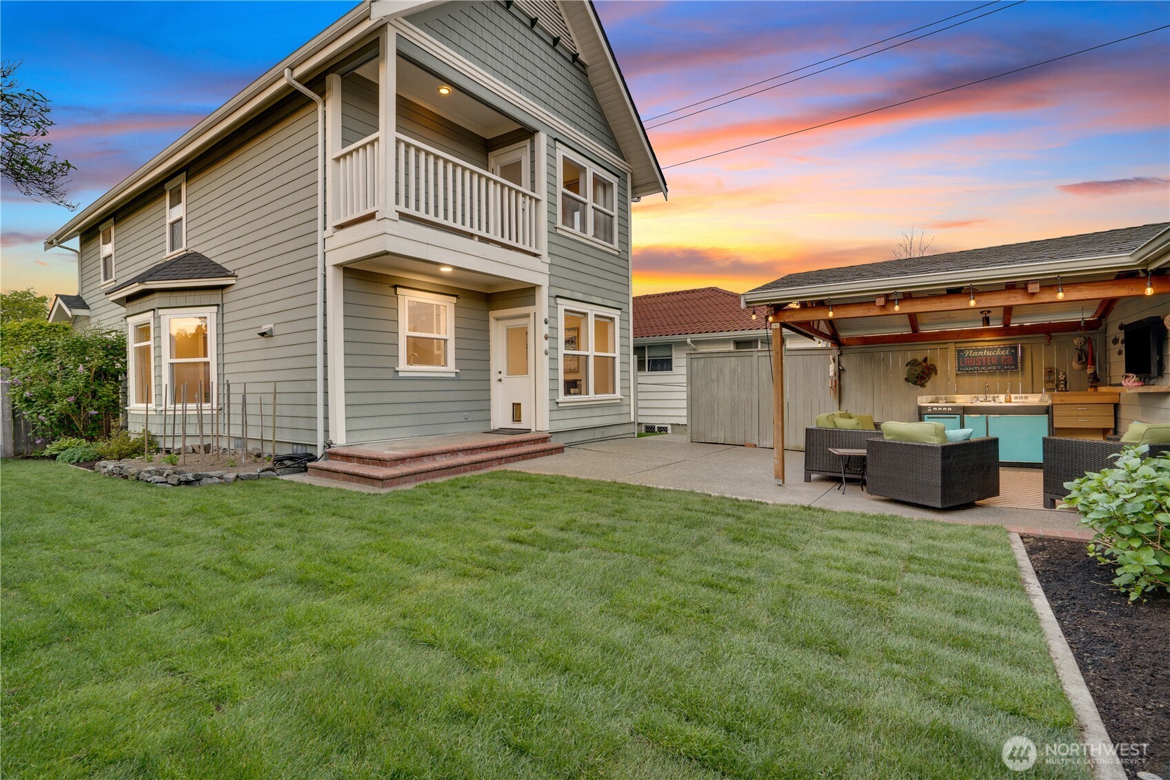 The whole compound at sunset — house, balcony, outdoor room, lawn. This is what 25 years of doing it right looks like from the backyard.