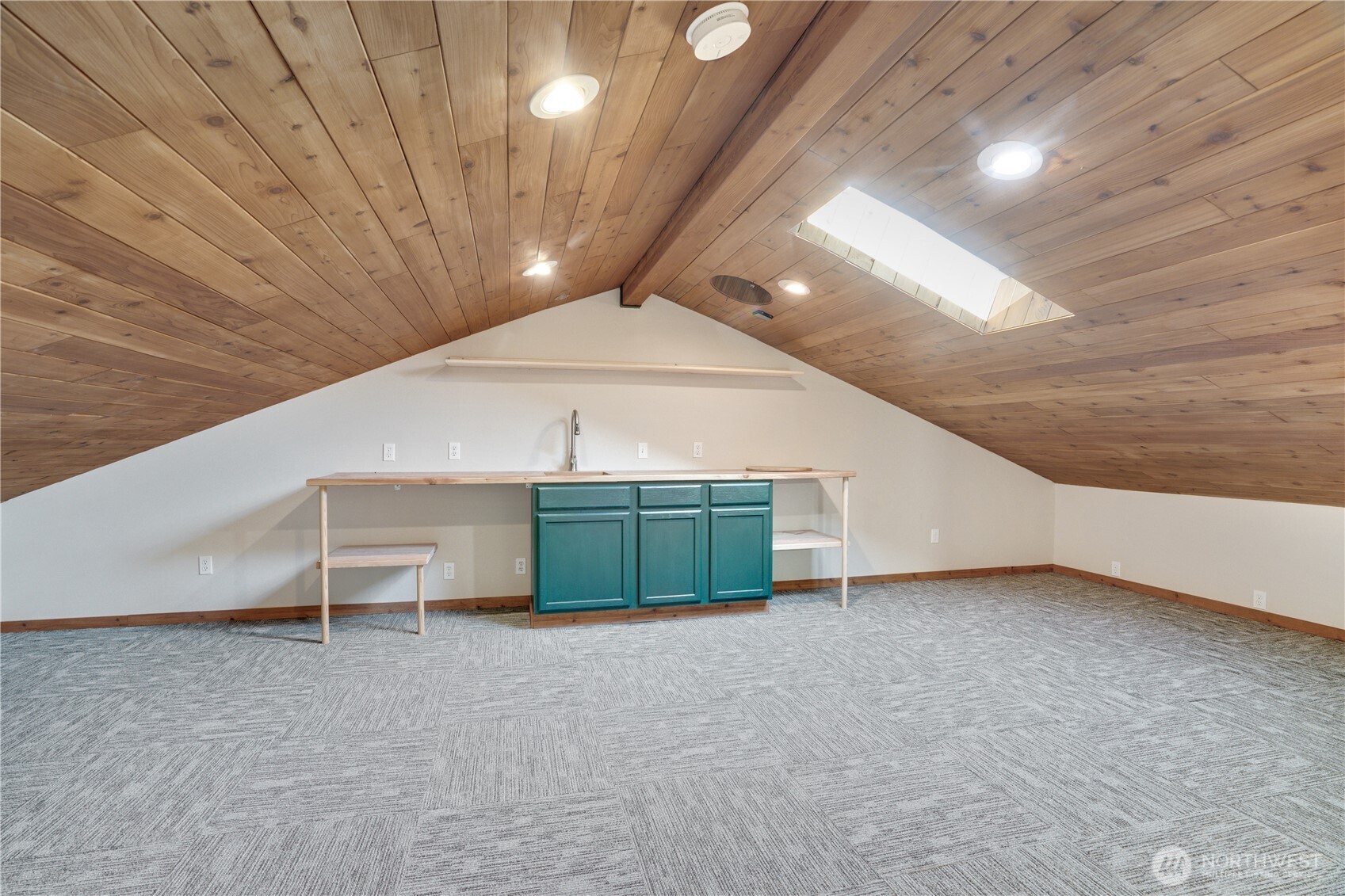 400 SF upstairs. Vaulted knotty pine ceiling. Skylight. Built-in work counter with sink. Cadet-heated. Commercial carpet. This loft means business — or whatever you need it to mean.