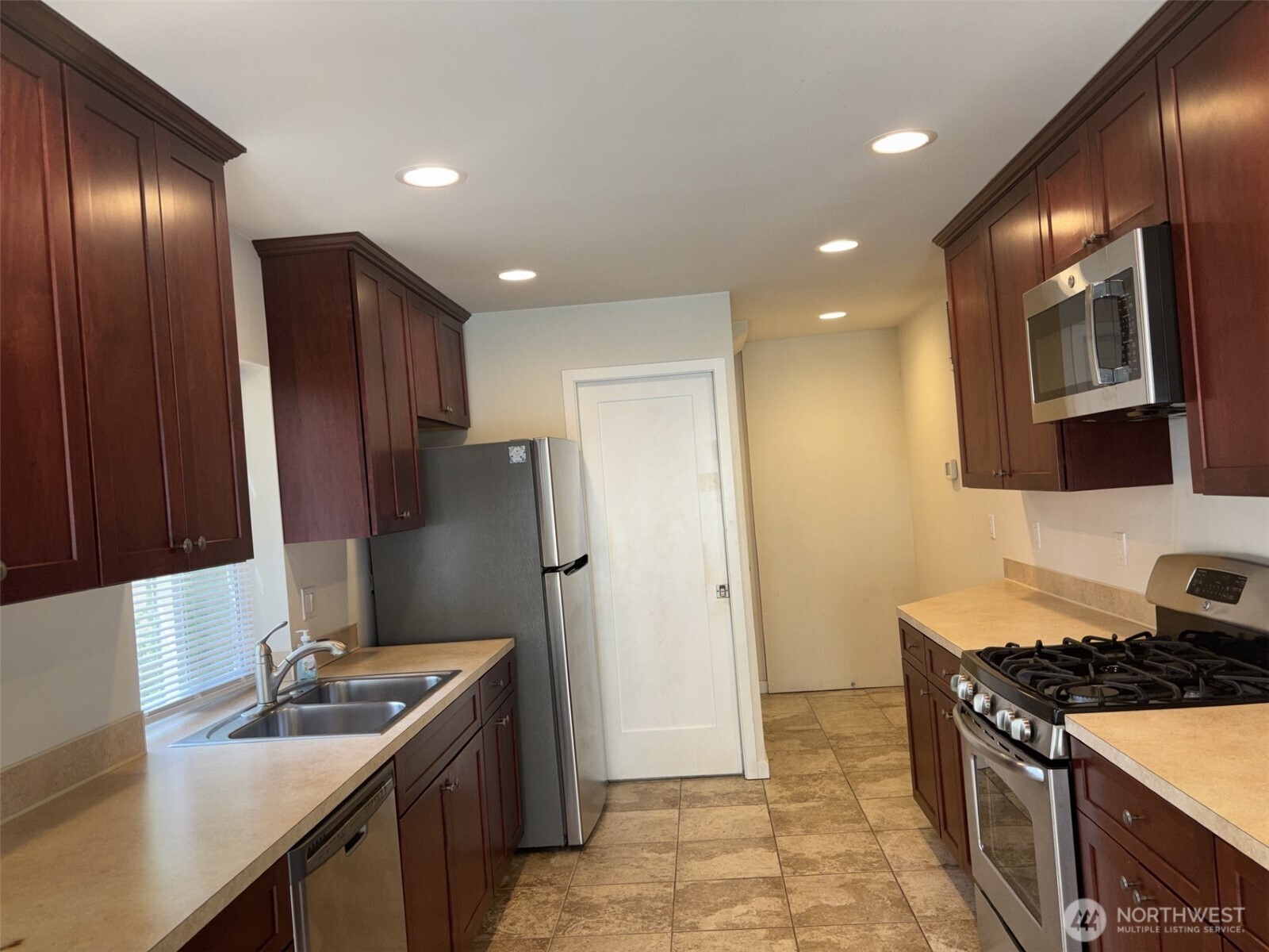 Large Galley kitchen with 2nd bathroom beyond. Ample cabinet package, gas cooktop and stainless steel appliances.