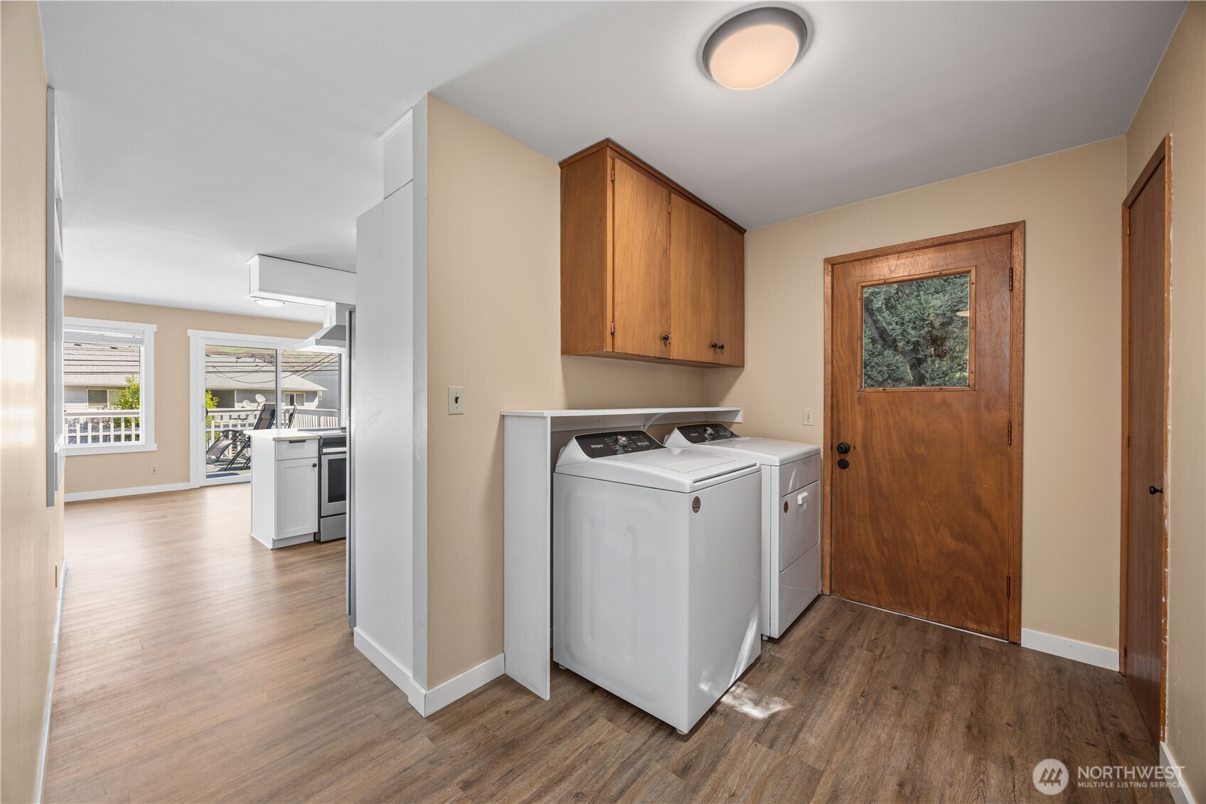 View of main level kitchen, dining and living room with fireplace and glass sliding doors leading to the lake view deck.