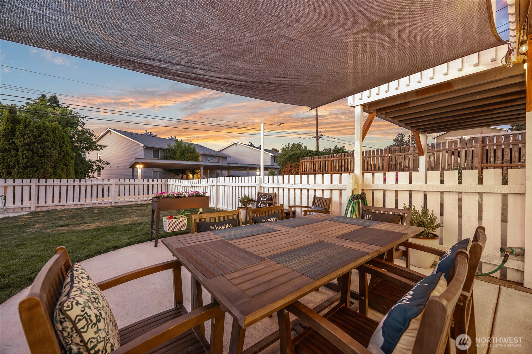 View of outdoor living and dining area and fenced backyard.