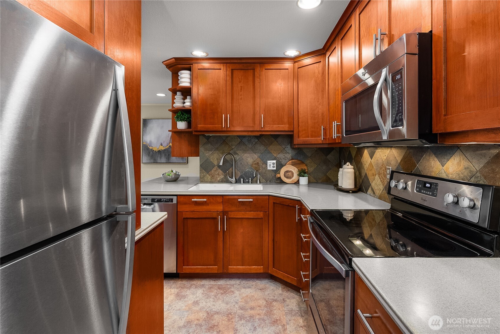Updated kitchen featuring wood cabinetry, tiled backsplash, and stainless steel appliances