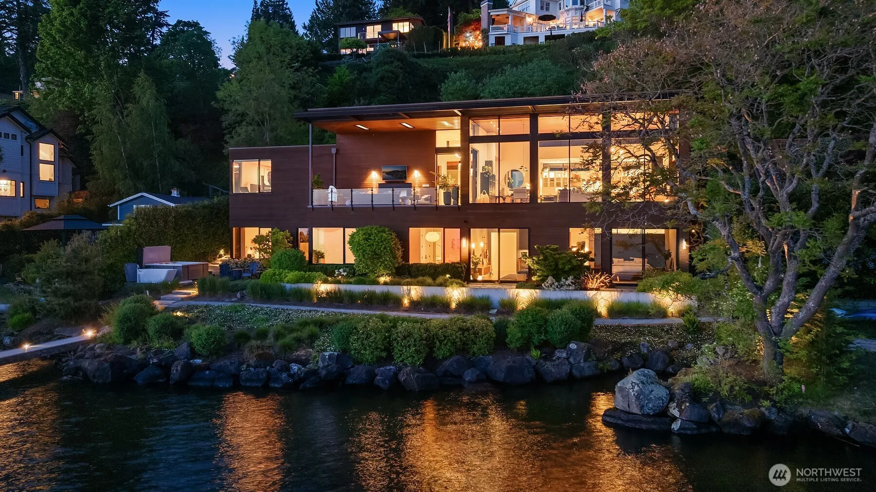 Twilight view of the home from the lake with a private dock and boat lift