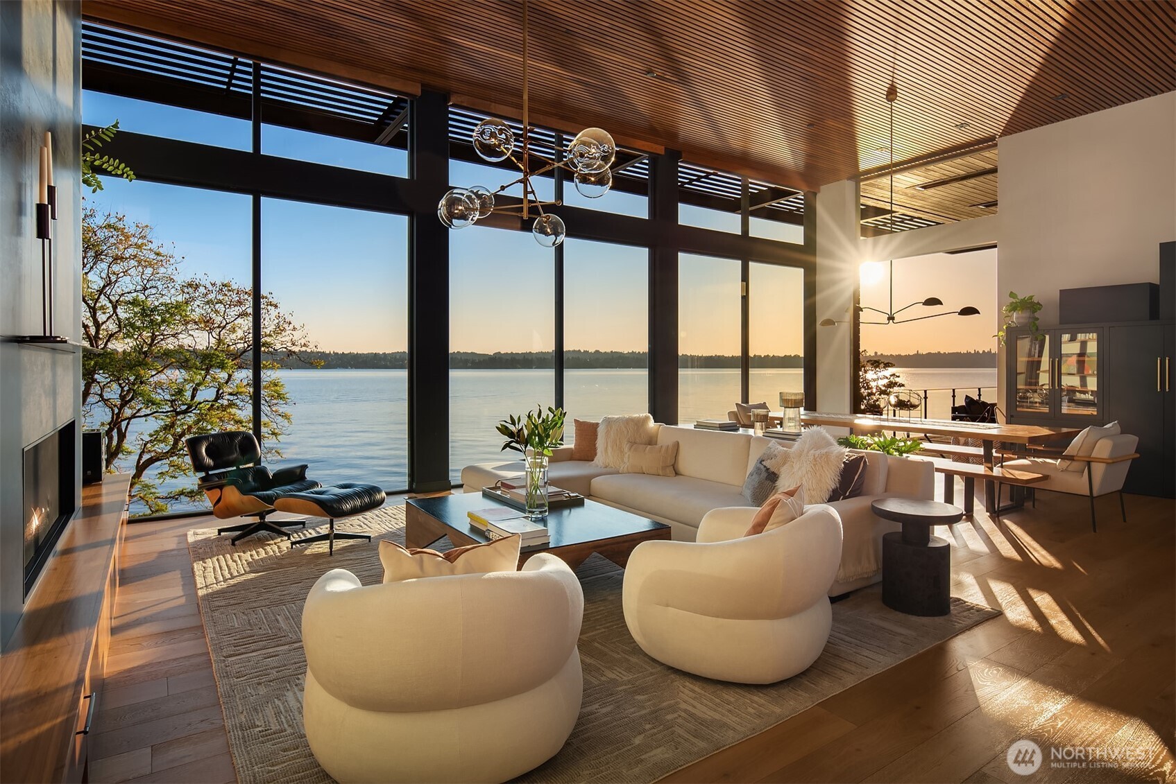 Open living and dining area with vaulted wood ceiling and floor-to-ceiling lake-view windows