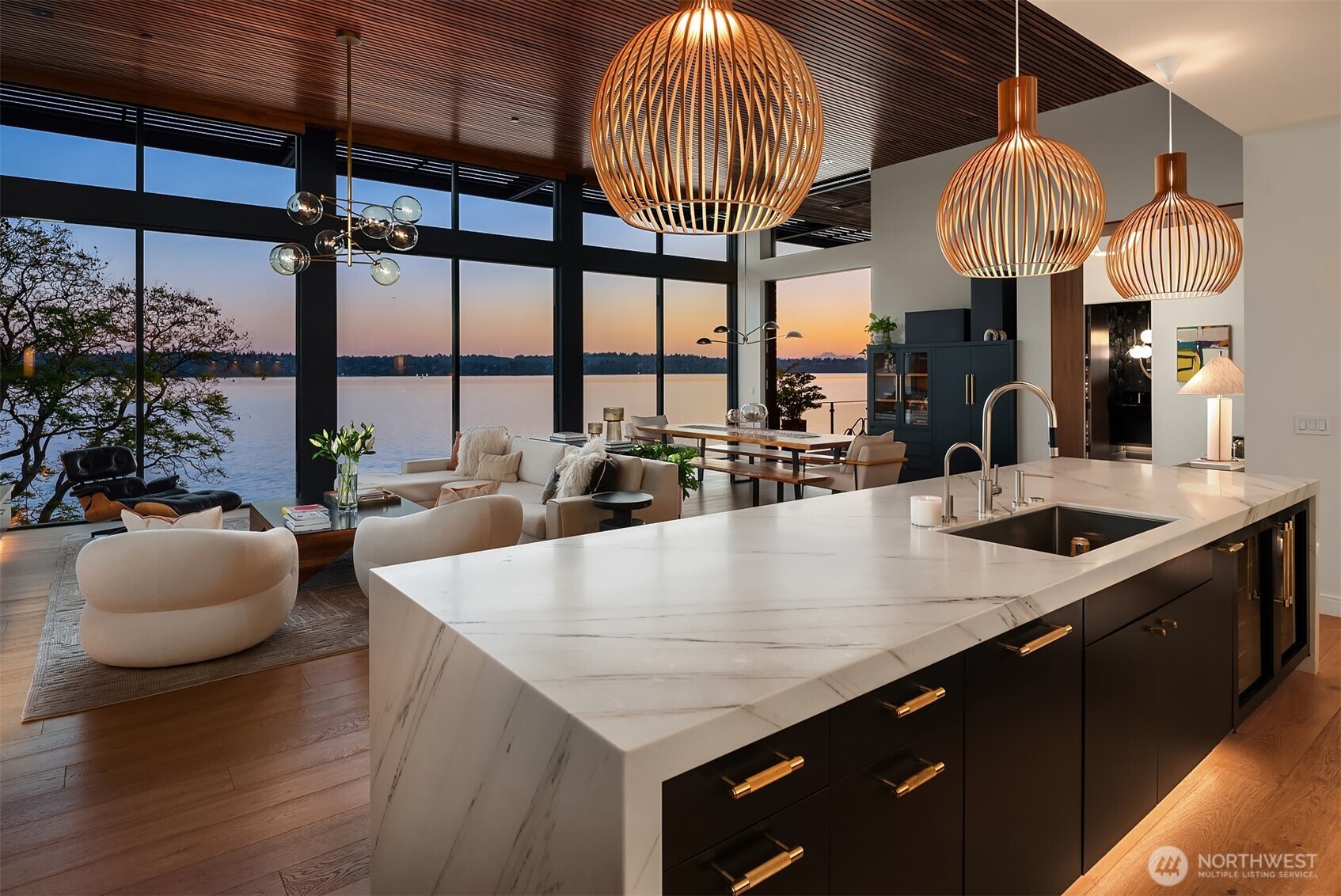 Living and dining area with fireplace and lake views at dusk